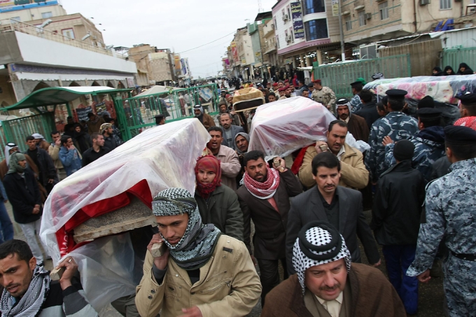 Iraqi mourners carry the coffins of vict